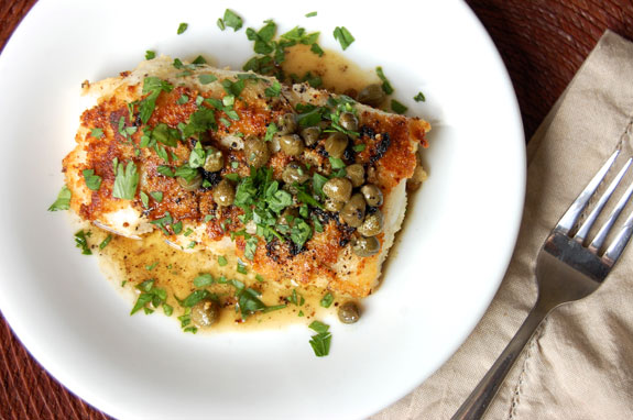 Image of Arctic Cod in a bowl, drizzled with a light sauce and garnished with capers and parsley.