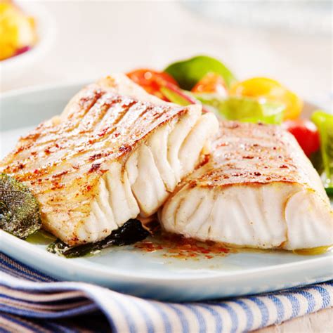 Image of grilled Pollock fish on a plate with some garnish.