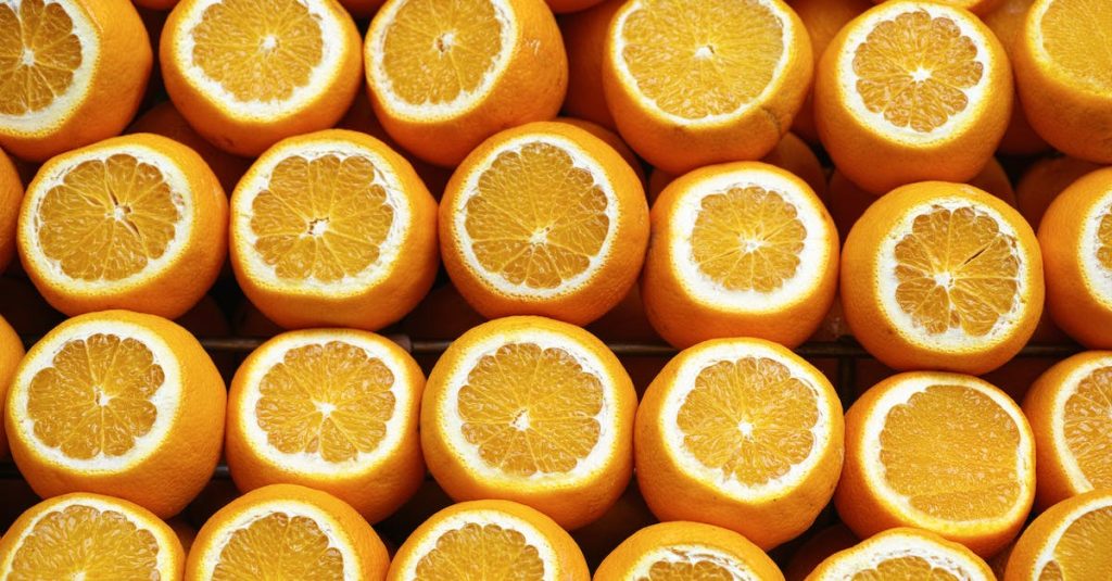 Image of many oranges, each cut horizontally so a cross-section of the segments is visible along with the orange outer rind.
