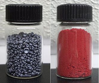 Image of two small glass jars. One holds small gray pellets and the other holds a course red powder.